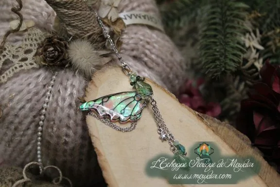 Pendentif papillon turquoise avec chainettes pendantes, gros plan sur bois