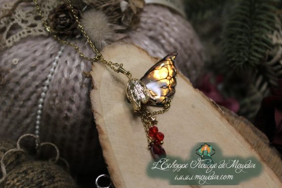 Pendentif aile doree avec perles rouges pendantes, gros plan sur bois