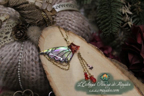 Pendentif aile turquoise avec perles rouges et pompons pendants, gros plan sur bois