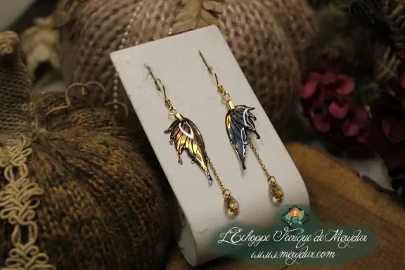 Boucles d'oreilles longues depareillees noires et violettes avec perle, sur carte