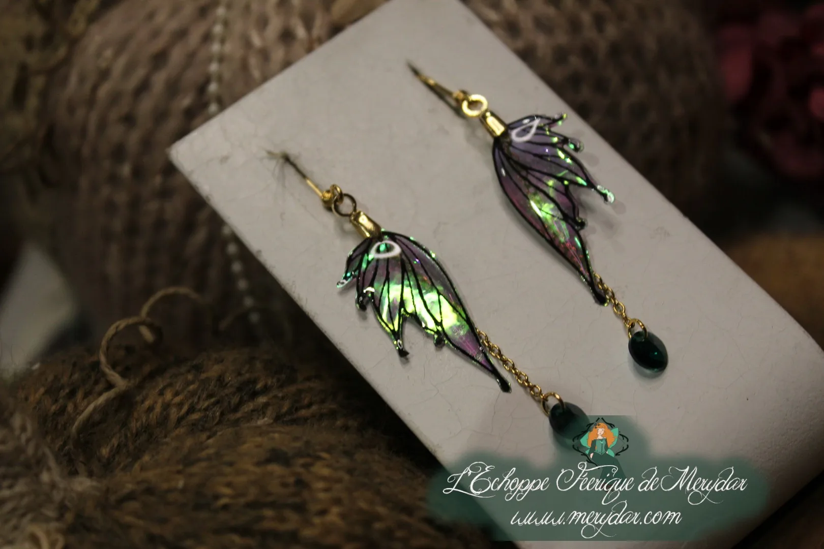 Boucles d'oreilles longues depareillees violettes et vertes avec chainette, sur carte