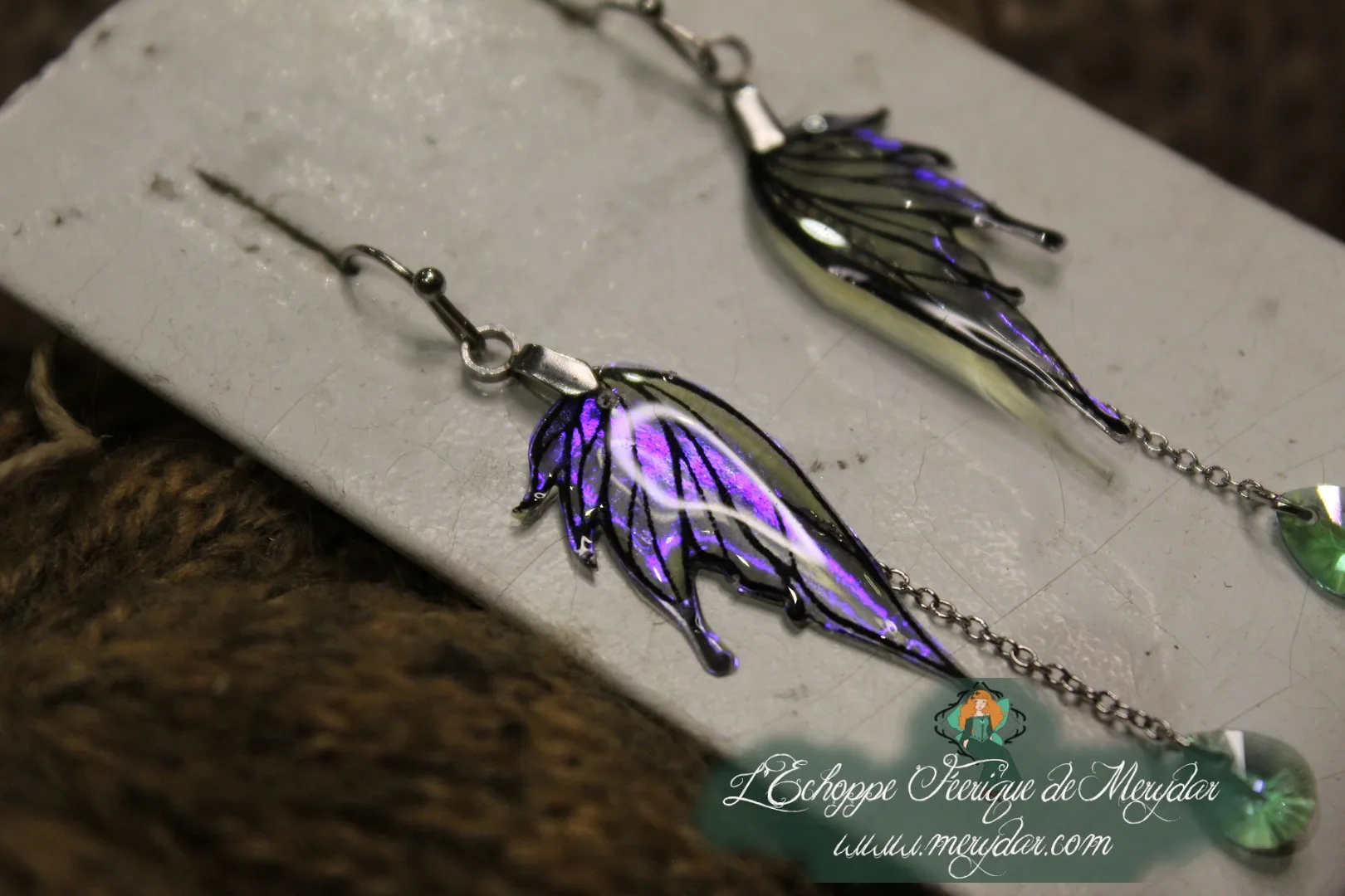 Boucles d'oreilles longues depareillees violettes, presentees sur carte
