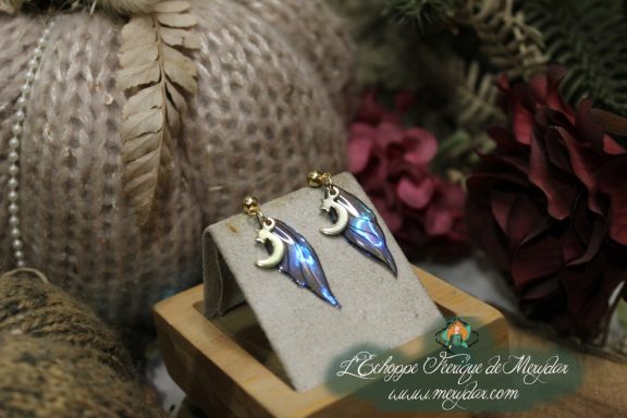 Boucles d'oreilles ailes de fee bleues, presentees sur socle en bois