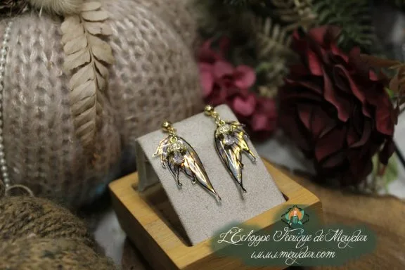 Boucles d'oreilles ailes de fee dorees, presentees sur socle en bois variante
