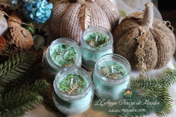 Groupe de bougies en pot cire verte pailletee, presentees sur decor automnal