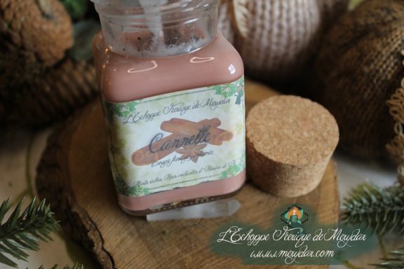 Bougie en pot cire rose avec etiquette Cannelle, presentee sur bois avec bouchon liege