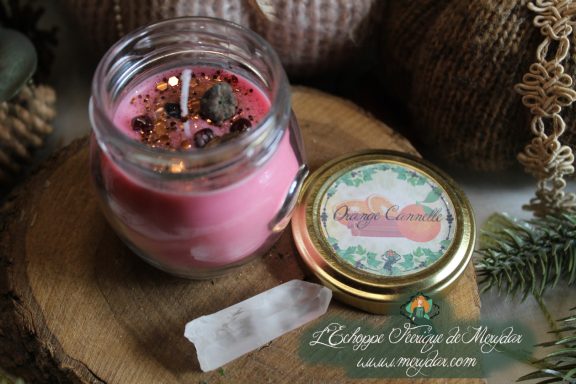 Bougie en pot cire rose avec etiquette Orange Cannelle, presentee sur bois