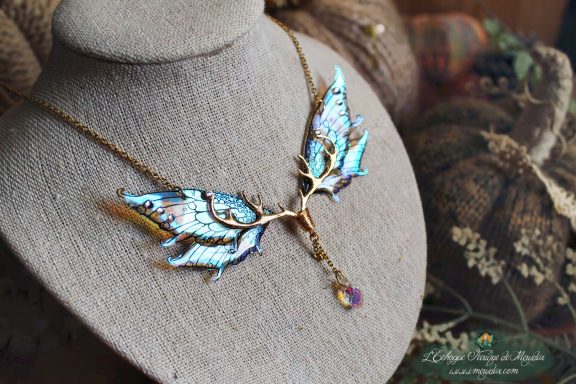 Collier pendentif branche doree avec aile bleue turquoise et perles, presente sur buste