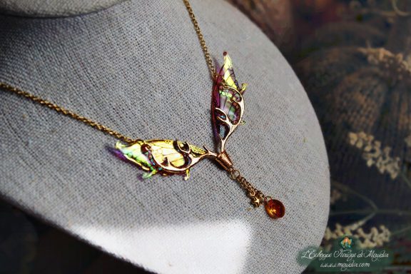 Collier pendentif branche doree avec deux ailes jaunes et perle ambree, presente sur buste
