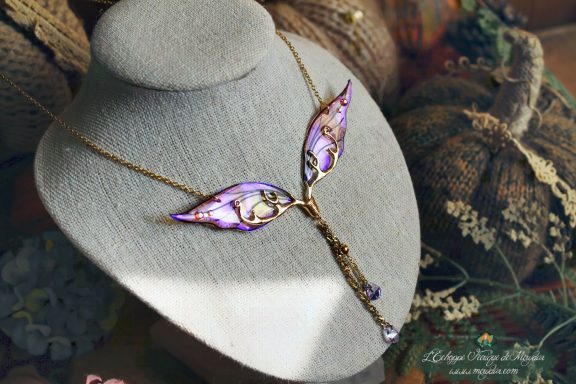Collier pendentif branche doree avec deux ailes violettes, presente sur buste porte-bijoux