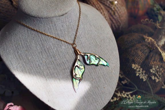 Petit pendentif branche doree avec deux petites ailes turquoise vertes, gros plan