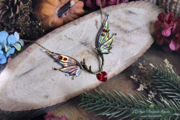 Collier pendentif bois de cerf avec deux ailes violettes roses et perle coeur rouge, gros plan