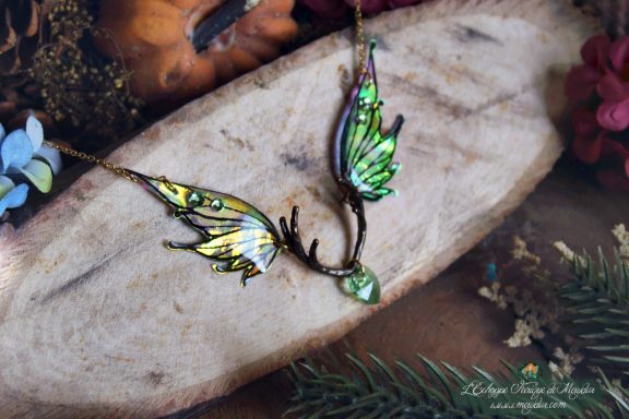 Collier pendentif bois de cerf avec deux ailes blanches jaunes et perle verte, gros plan