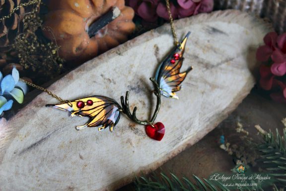 Collier pendentif bois de cerf avec deux ailes orange jaunes et perle coeur rouge, gros plan