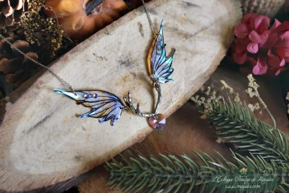 Collier pendentif bois de cerf avec deux ailes bleues turquoise et perle violette, presente sur bois