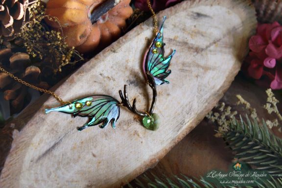 Collier pendentif bois de cerf avec deux ailes turquoise vertes et perle verte, presente sur bois