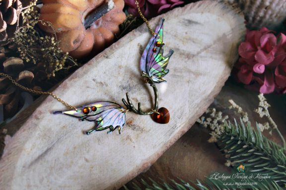 Collier pendentif bois de cerf avec deux ailes turquoise violettes et perle coeur rouge, gros plan