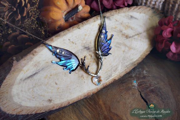 Collier pendentif bois de cerf avec aile bleue violette et perle transparente, gros plan