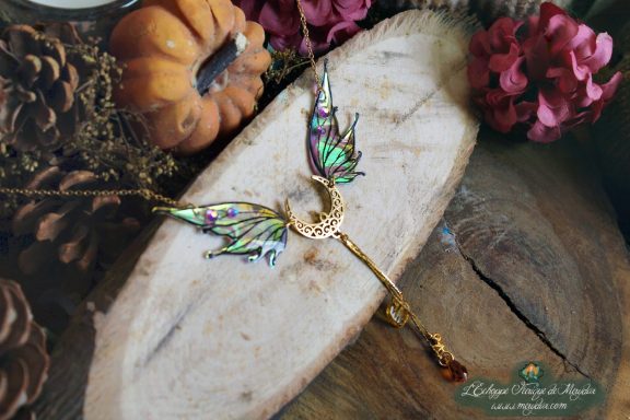 Collier pendentif aile turquoise avec breloque lune, presente sur bois