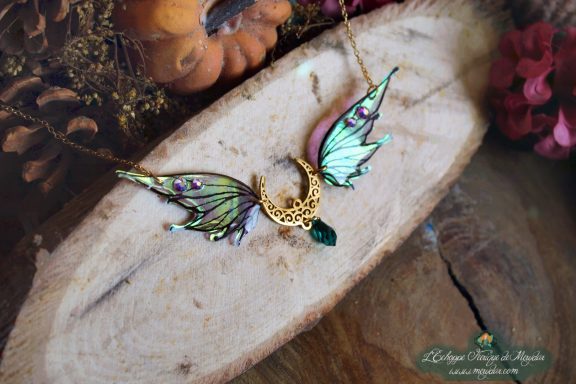 Collier pendentif aile turquoise verte avec breloque lune, presente sur bois