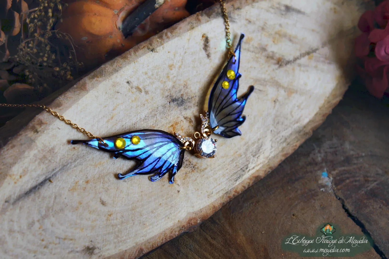 Collier pendentif aile bleue violette avec breloque lune, gros plan sur bois