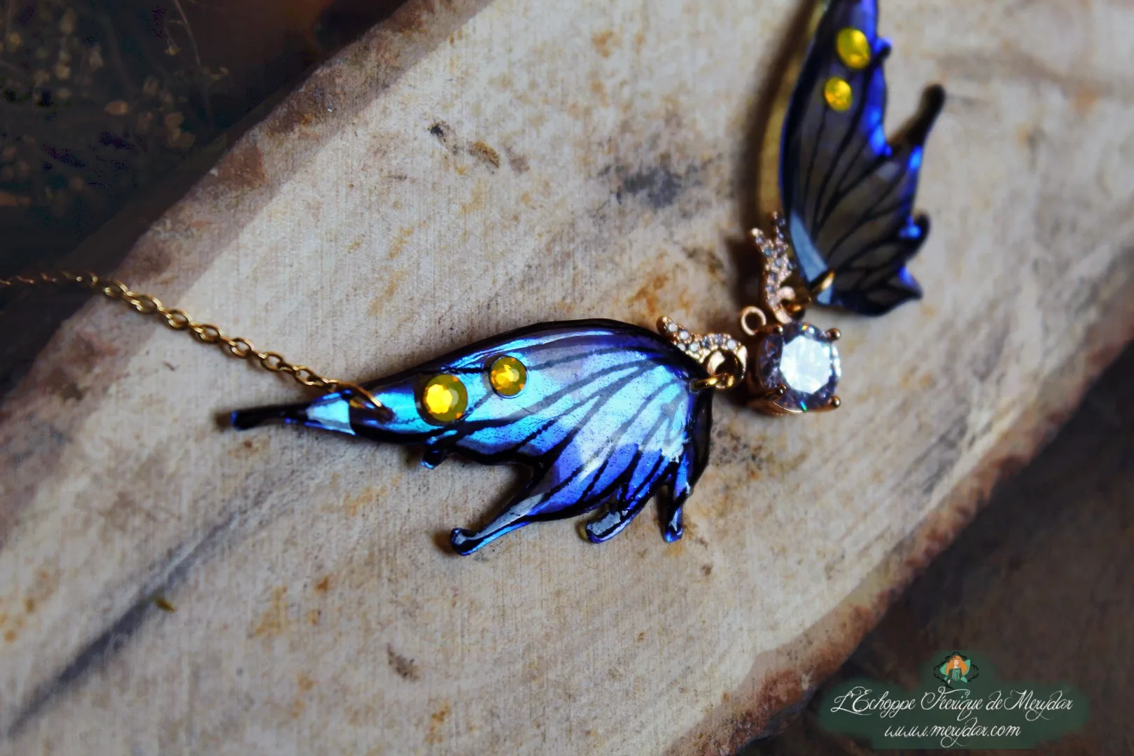 Collier pendentif aile bleue avec breloque lune et pierre transparente, presente sur bois