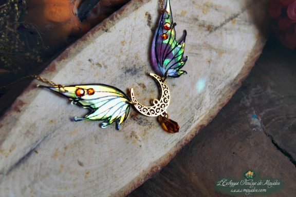 Collier pendentif aile verte violette avec breloque lune et pierre, gros plan sur bois