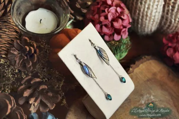 Boucles d'oreilles longues aile turquoise avec perle turquoise, presentees sur socle