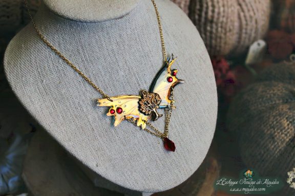 Collier pendentif renard aile jaune orange avec perles rouges, presente sur buste porte-bijoux