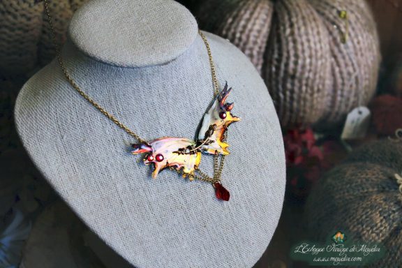 Collier pendentif renard aile rose blanche avec perle rouge, presente sur buste porte-bijoux