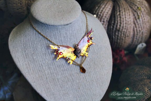 Collier pendentif renard aile violette jaune avec perles rouges, presente sur buste porte-bijoux