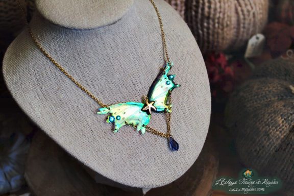 Collier pendentif renard aile turquoise avec breloque etoile et perle bleue, presente sur buste