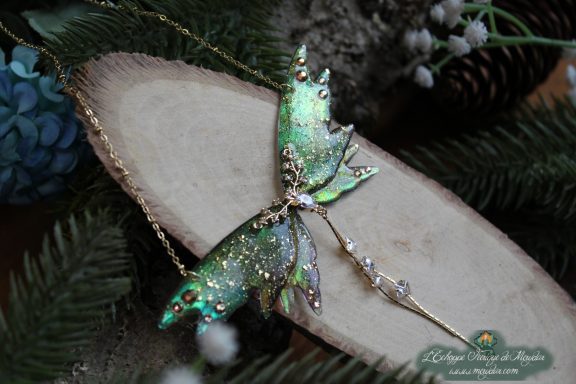 Collier pendentif aile de mite cosmique verte entiere avec epingle pendante, sur bois