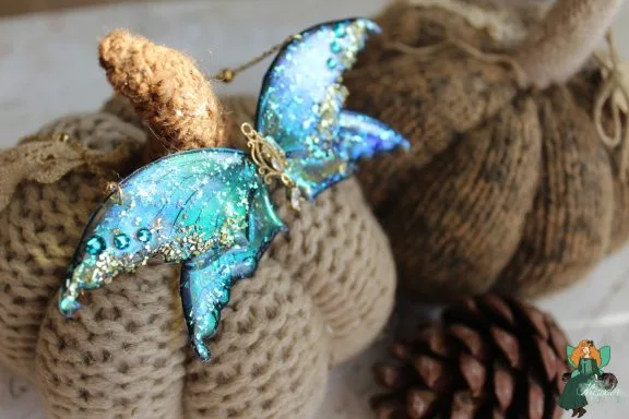 Pendentif aile de chauve-souris bleue pailetee avec antennes dorees
