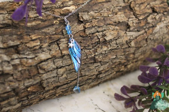 Pendentif aile plume bleue avec perle bleue pendante, sur ecorce
