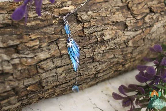 Pendentif aile plume bleue avec perle bleue pendante, sur ecorce