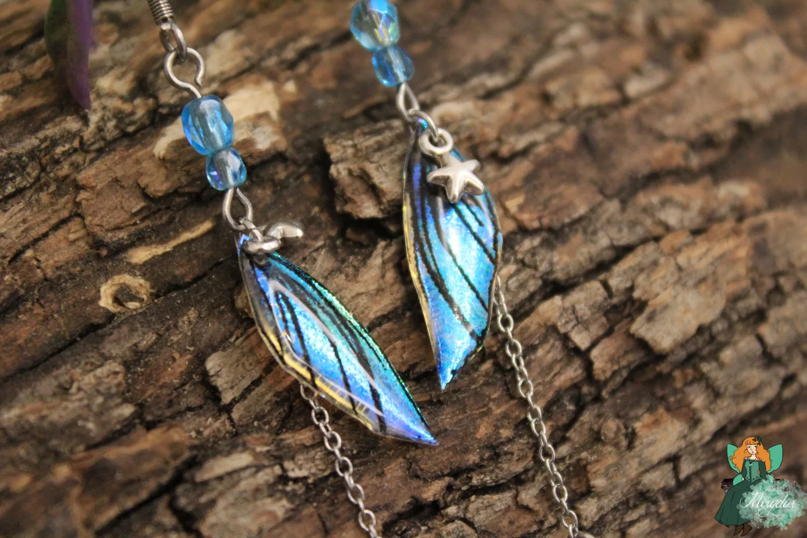 Boucles d'oreilles aile plume bleue avec breloque etoile, gros plan