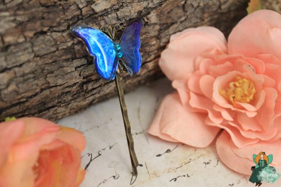 Epingle a cheveux papillon bleu, presentee sur fleur rose