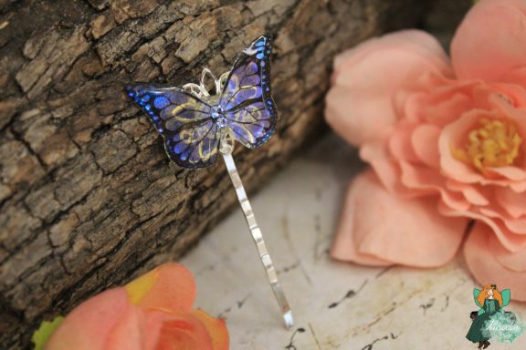 Epingle a cheveux papillon bleu violet, presentee sur fleur rose