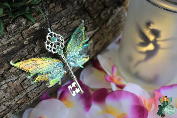 Pendentif cle ailee verte pailetee, presente sur fleurs