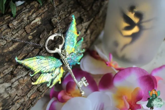 Pendentif cle ailee verte irisee, presente sur fleurs