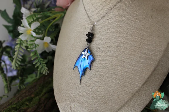 Pendentif aile de dragon bleue avec breloque etoile et perles sombres, sur buste