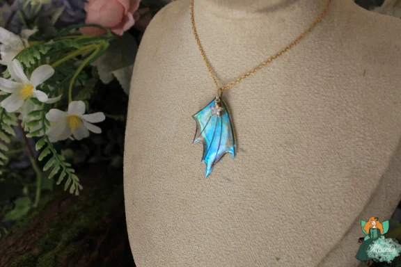 Petit pendentif aile de dragon turquoise, chaine doree sur buste