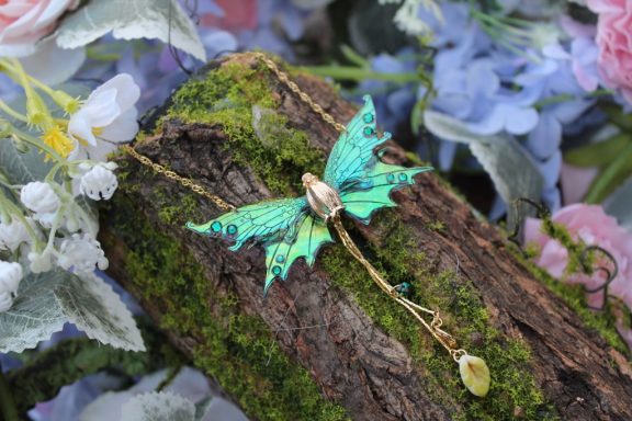 Pendentif papillon aile violette verte avec breloque etoile doree, sur bois