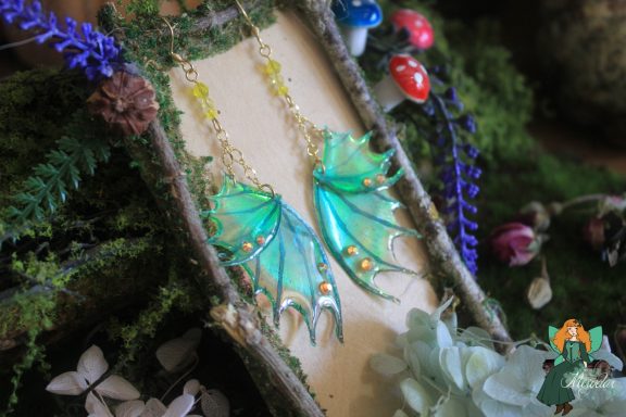 Boucles d'oreilles aile de dragon jaune turquoise, presentees sur presentoir
