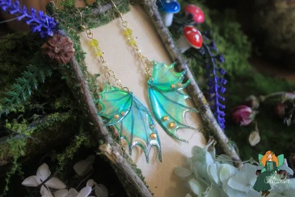 Boucles d'oreilles aile de dragon jaune turquoise, presentees sur presentoir