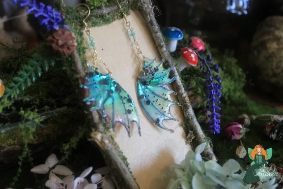 Boucles d'oreilles aile de dragon turquoise, presentees sur presentoir bois