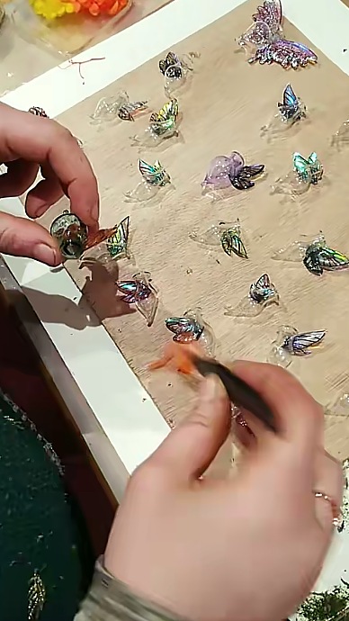Deux mains posant des ailes sur une rangée de fioles