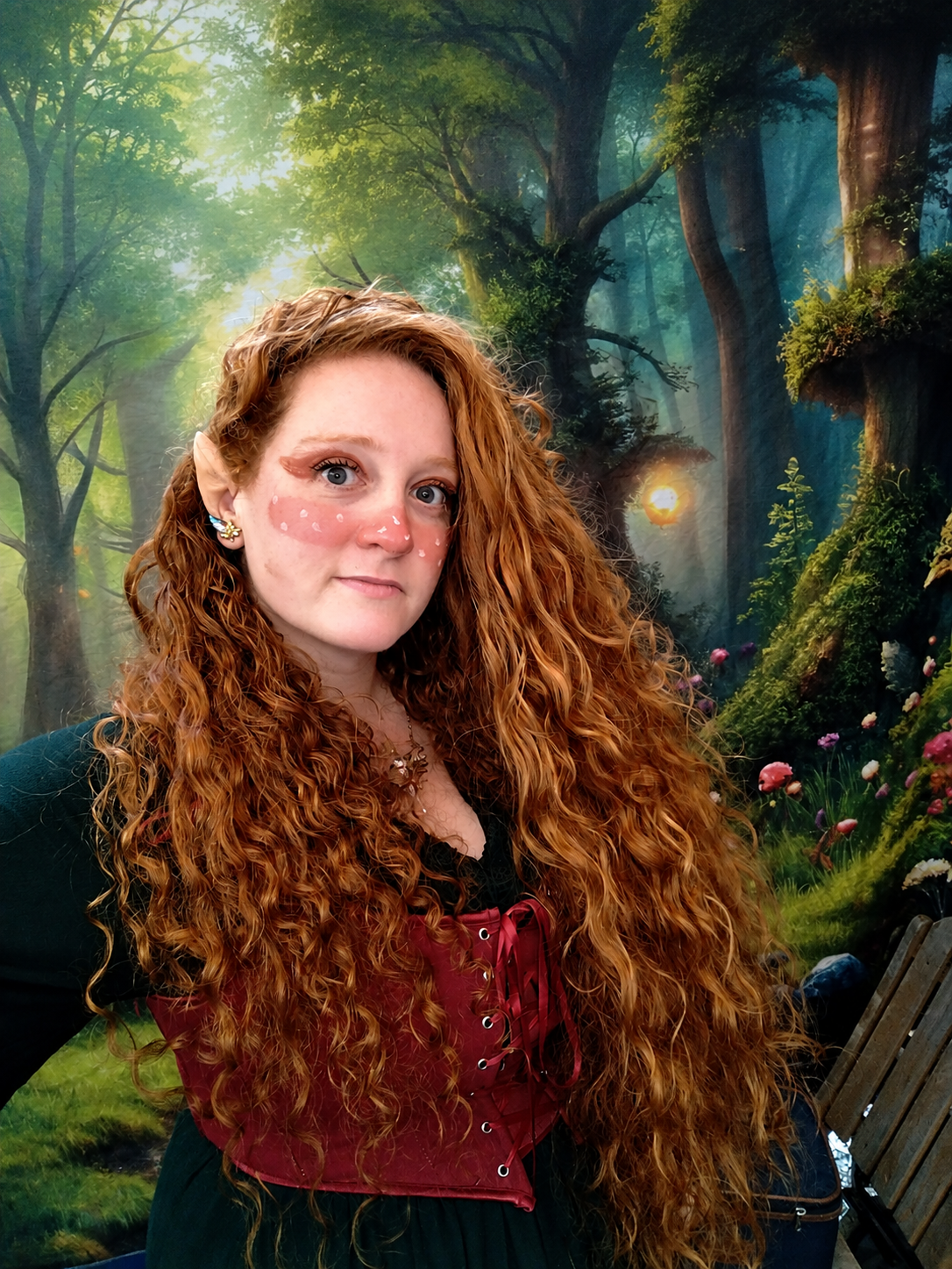 Portrait d'une femme aux cheveux roux boucles en foret, robe bordeaux